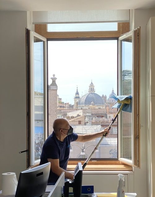 uomo che pulisce una vetrata a roma dipendente dell'azienda adrianea